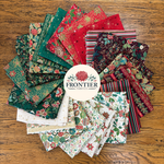A circular arrangement of multiple folded fabric swatches in assorted holiday-themed patterns and colors, including red, green, black, white, and striped designs, with a white circular logo in the center reading FRONTIER FABRICS, placed on a wooden surface.