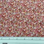 A close-up of a floral fabric pattern with small pink, white, and yellow flowers, shown with a metal ruler at the bottom for scale.