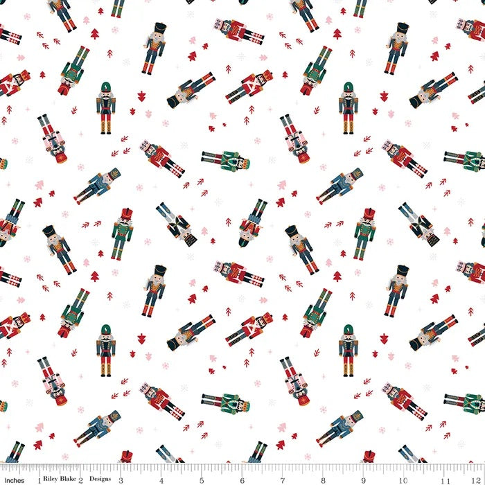 Riley Blake Nutcracker Tradition Magic Snow fabric featuring colourful nutcracker soldiers, tiny red Christmas trees and snowflakes scattered on a white background.
