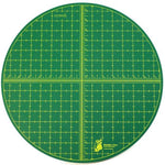 Round green cutting mat with grid lines and measurements on a white background